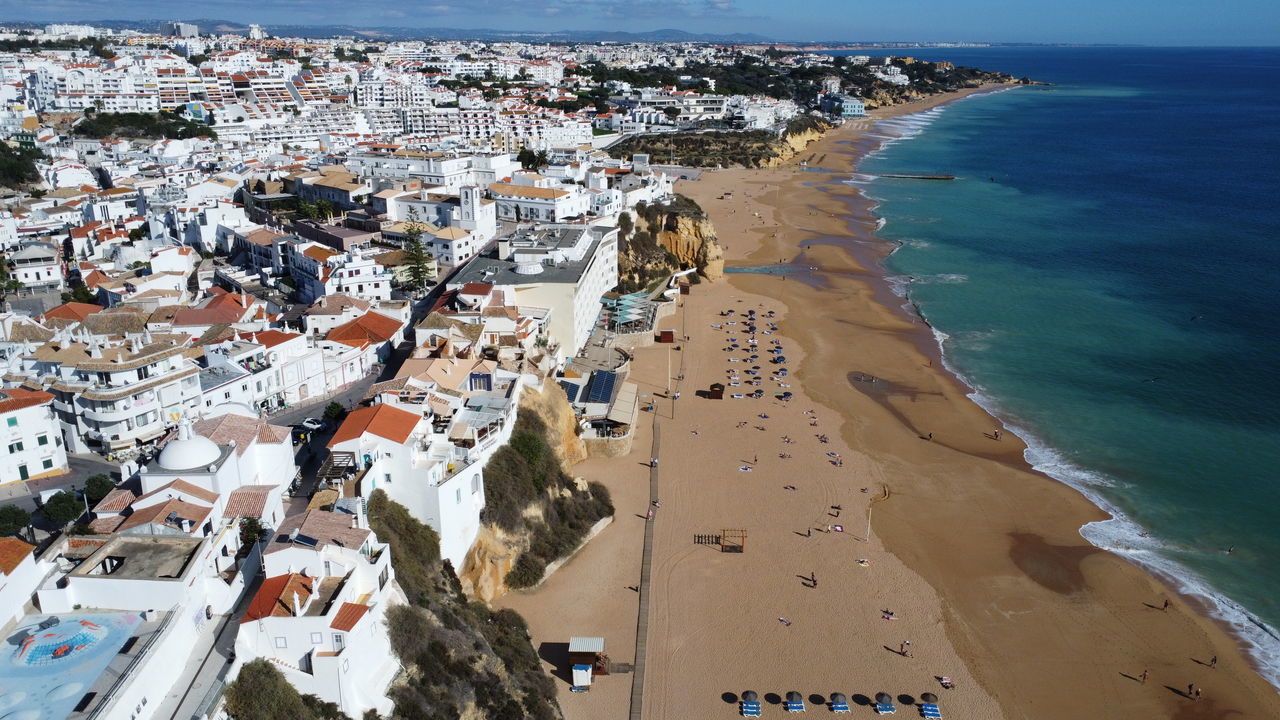 sea, water, land, beach, architecture, coast, nature, building exterior, high angle view, city, travel destinations, coastline, travel, building, environment, built structure, scenics - nature, sky, aerial view, tourism, aerial photography, beauty in nature, sand, landscape, holiday, vacation, outdoors, trip, day, horizon over water, house, body of water, no people, transportation, horizon, residential district, water's edge, cityscape, ocean, shore, summer, sunlight, sunny, town, nautical vessel