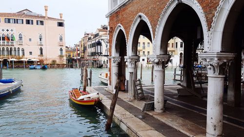 Gondola moored in canal by building in city