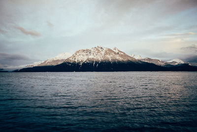 Scenic view of sea and snowcapped mountains against sky