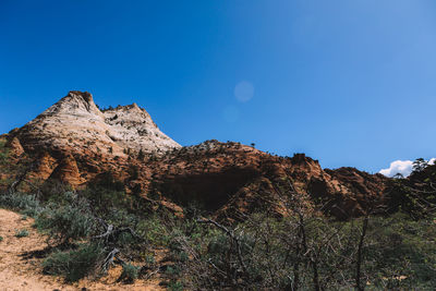 Low angle view of rocky mountains against clear blue sky