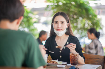 Portrait of young woman holding drink at restaurant table