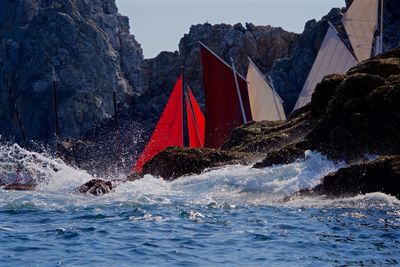 Sailboats in river against rock formations