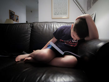 Midsection of boy sitting on sofa at home