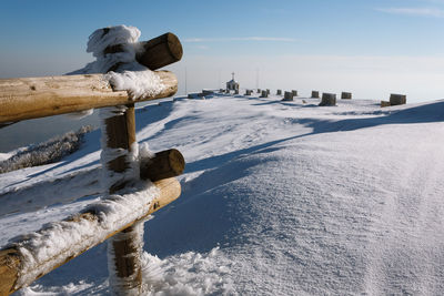 Wooden posts on snow covered land against sky