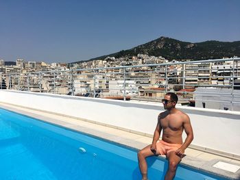 Shirtless man at swimming pool against sky