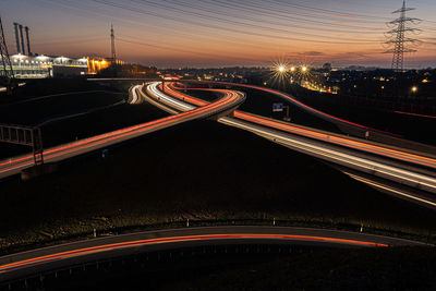 Light trails on road in city against sky at night