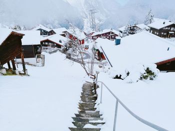 Snow covered houses by city against sky