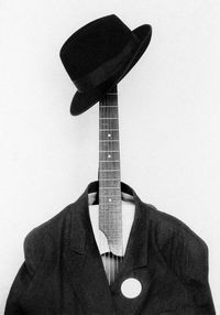 Close-up of hat and suit on guitar against white background