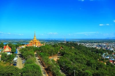 Panoramic view of trees and buildings against blue sky