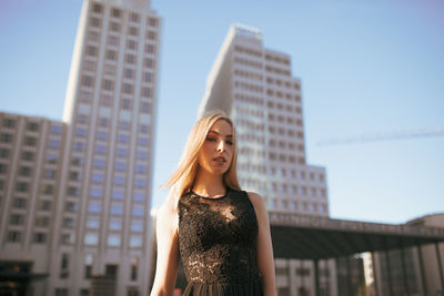Portrait of beautiful woman standing against buildings