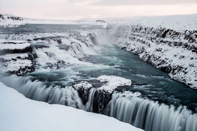 Scenic view of waterfall against sky during winter