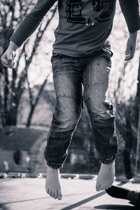 Low section of boy jumping on trampoline