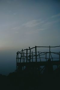 Silhouette fence against sky at sunset