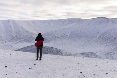 Rear view of woman standing on snowcapped mountain against sky