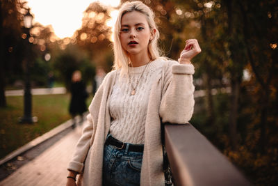 Portrait of young woman standing against trees