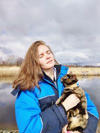 Happy woman with dog against sky