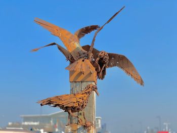 Low angle view of sculpture against clear blue sky