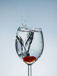 Close-up of water splashing on glass against white background