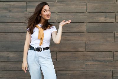 Young woman standing against wall