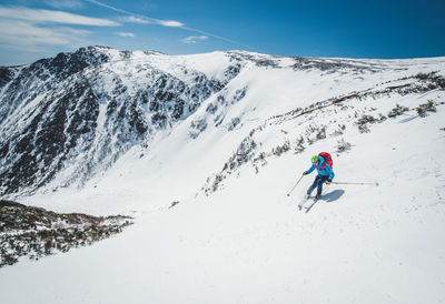 Man skiing on snowcapped mountain against sky