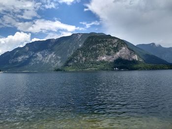 Scenic view of sea by mountains against sky