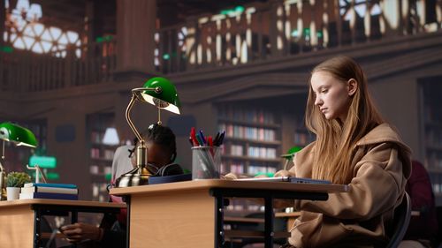 Young woman using mobile phone while sitting on table