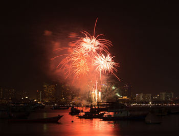 Firework display in city against sky at night