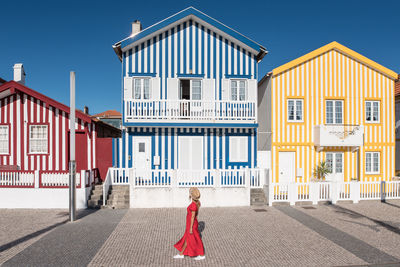 Side view of unrecognizable female tourist contemplating house exteriors with striped ornament while walking on costa nova in aveiro portugal