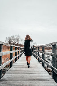 Rear view of woman walking on footbridge