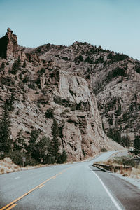 Road leading towards mountains against clear sky