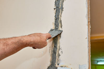 Close-up of man working on wood against wall