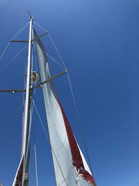 Low angle view of sailboat in sea against clear blue sky