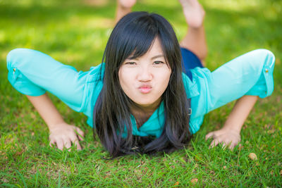 Portrait of smiling woman lying on grass at park