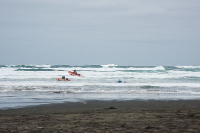 People at beach against sky