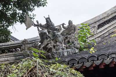 Low angle view of statue by building against sky