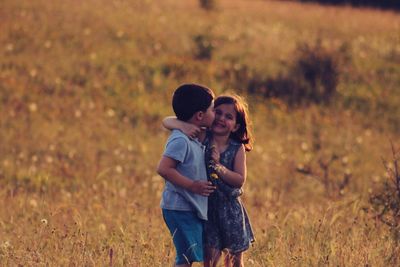 Boy kissing friend while standing on field