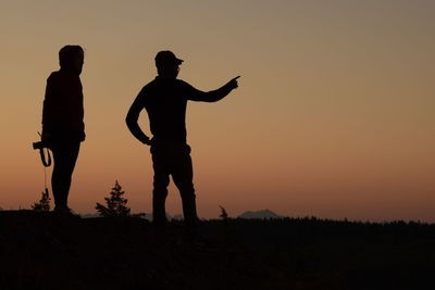 Silhouette men standing against sky during sunset