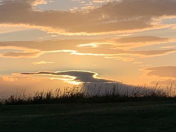 Scenic view of silhouette field against sky during sunset