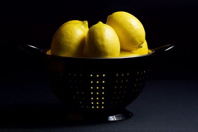 Close-up of lemons in bowl against black background