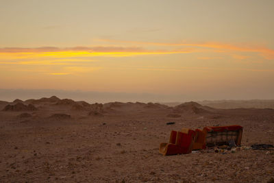 Vintage sofa throwed into garbage in the middle of the desert during golden sunset