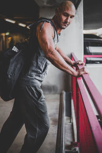 Side view of muscular man leaning on railing