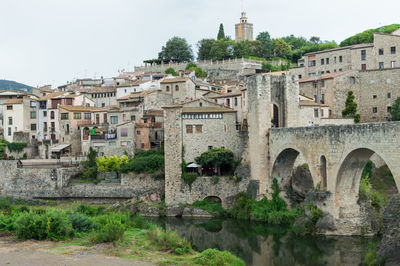 Arch bridge over river against buildings