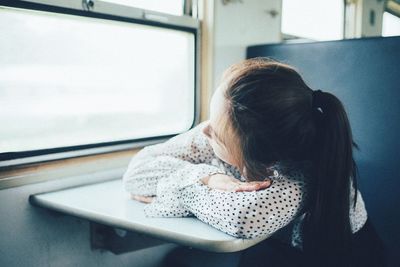 Young woman looking through window while traveling in train