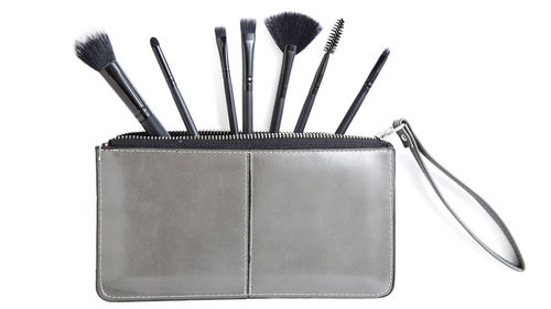 Close-up of purse and make-up brushes over white background