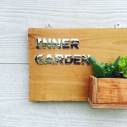 Metallic text on plank with succulent plants mounted on wall