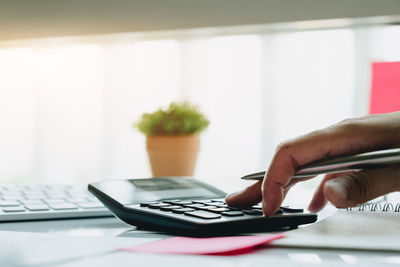 Cropped hand using calculator at desk