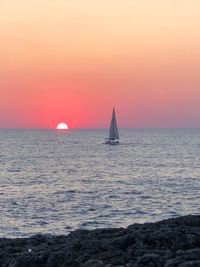 Sailboat sailing on sea against sky during sunset