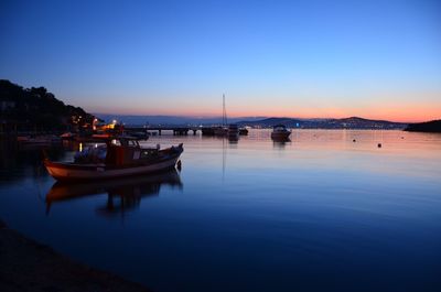 Boats in calm sea at sunset