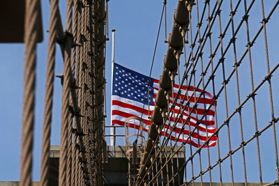 Low angle view of fence by american flag against clear sky