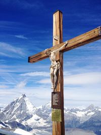 Information sign on snowcapped mountain against blue sky